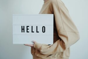 A person holding a lightbox displaying the word 'HELLO' on a white background.