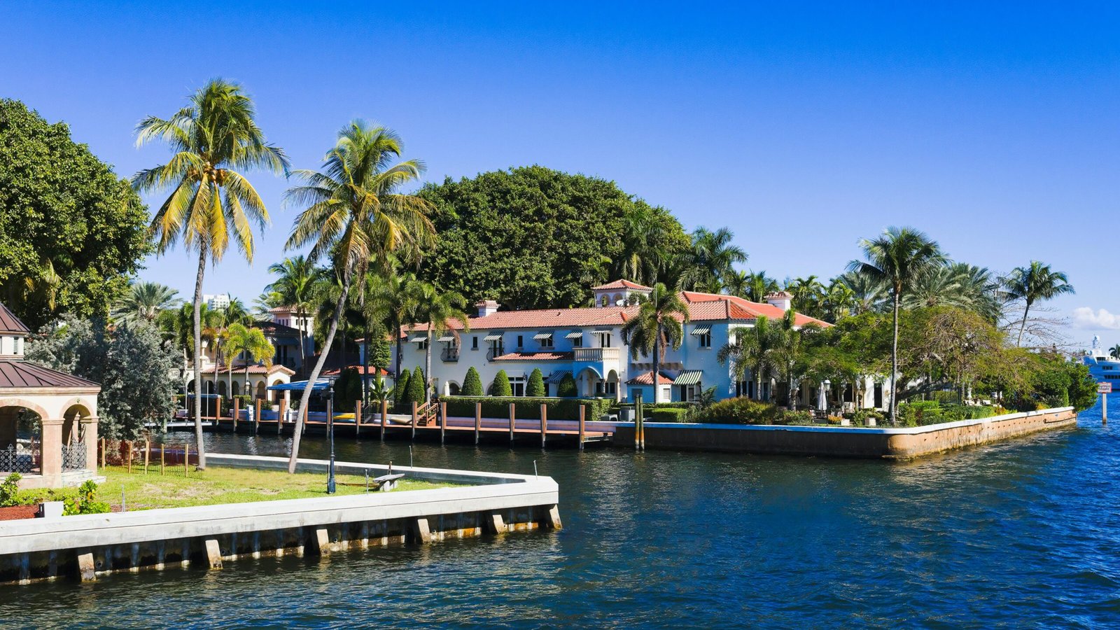 Beautiful tropical homes along a canal with palm trees and clear blue sky in Fort Lauderdale, Florida.