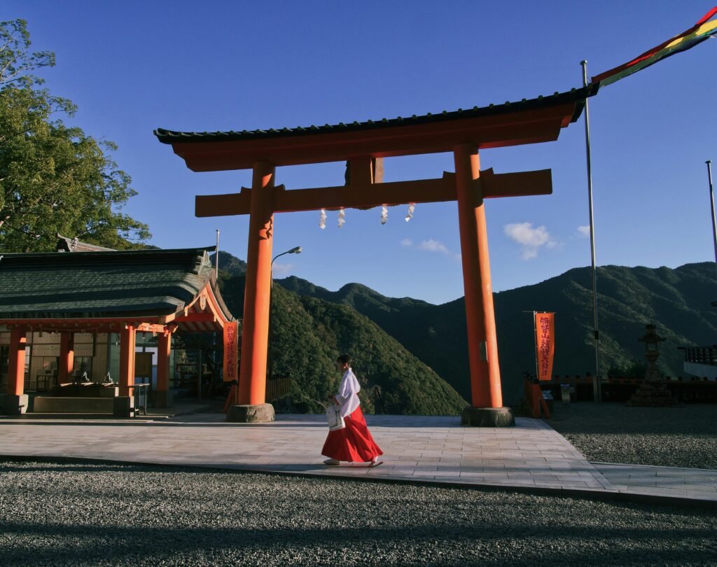 Useful Japanese Etiquette for Tourists: Essential Tips Before You Visit 7 Woman walks through a traditional Shinto torii gate at a serene shrine during daylight.