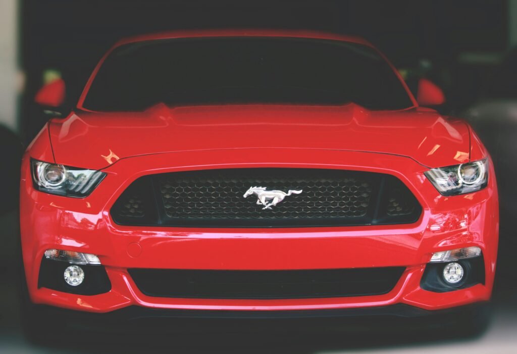 Japanese Cars vs American Cars: A Traveler's Eye-Opening Journey from Tokyo Streets to American Highways 2 Bright red Ford Mustang showcased with a sleek front view in Ahmedabad.